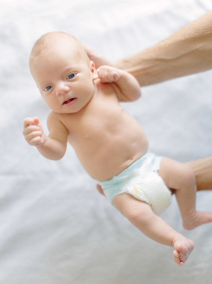 Noworodek trzymany na rękach podczas sesji rodzinnej w Poznaniu